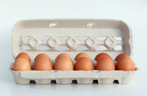 Cierre de huevos marrones en caja de cartón sobre fondo blanco - Foto, imagen