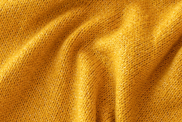 Morbido maglione giallo maglia trama primo piano. Luce arancione sfondo astratto - Foto, immagini