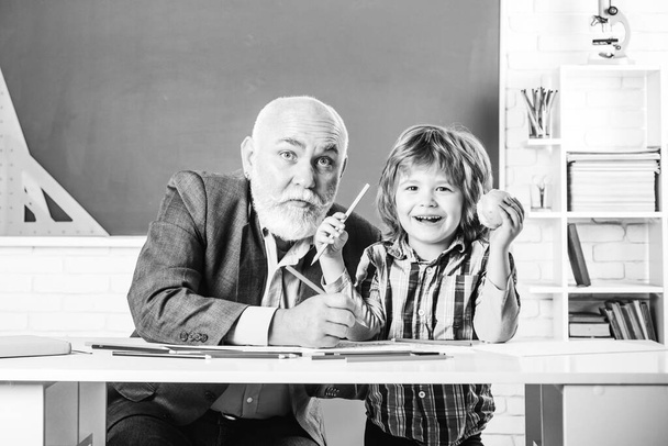 Portrait of happy grandfather and Son in classroom. Grandfather and grandchild - generation people concept. A grandfather and a son are learning in class. Back to school. - Фото, изображение