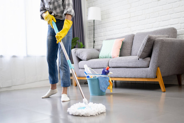 Image recadrée d'une adolescente tenant un bâton de serpillière faisant des tâches ménagères nettoie le salon - Photo, image