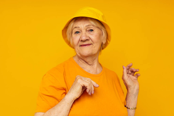 elderly woman happy lifestyle in a yellow headdress yellow background - Fotoğraf, Görsel