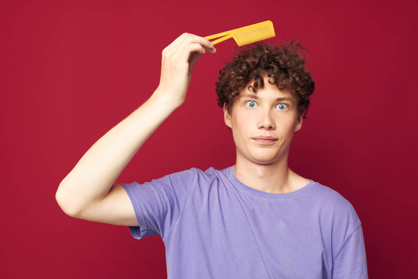 guy with red curly hair in purple t-shirts with a comb isolated background - Photo, image