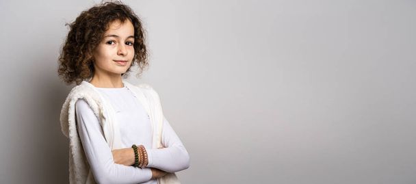 One small caucasian girl ten years old with curly hair front view portrait close up standing in front of white background looking to the camera smiling happy and joy copy space - Foto, Bild