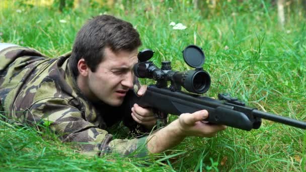 El hombre apunta desde un rifle de francotirador mientras está tendido en una emboscada. Imágenes de 4k - Metraje, vídeo