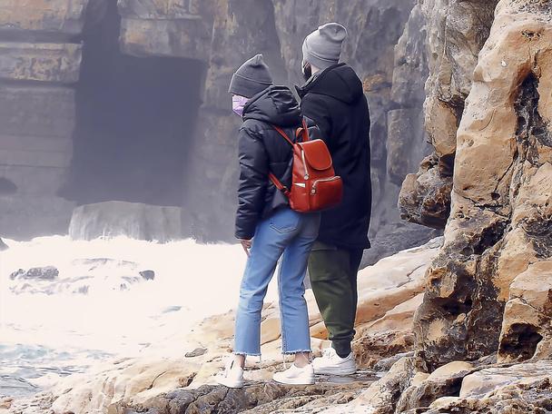 A couple of young people on a rocky shore overlooking the ocean - Foto, Bild