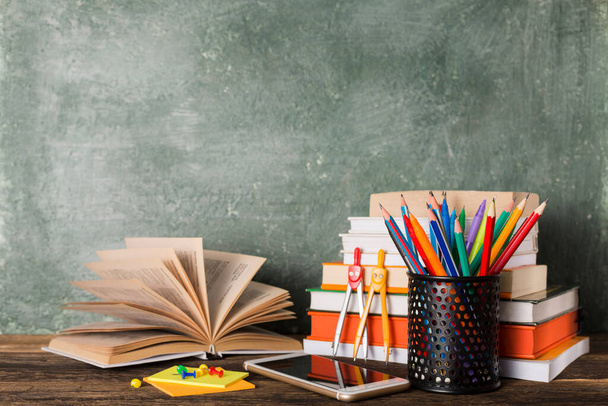 Stack of books and stationery on the background of the school board. Education and back to school concept. - Photo, Image
