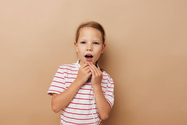 Portrait of happy smiling child girl in striped t-shirt headphones gesture hands childhood unaltered - Φωτογραφία, εικόνα