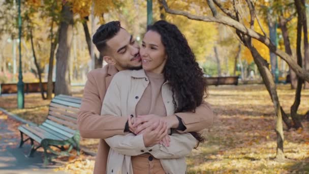 Hispanic family hugging standing in autumn park young couple smiling talking romantic date outdoors guy and girl enjoying conversation embrace planning joint happy life feeling love enjoy each other - Materiał filmowy, wideo