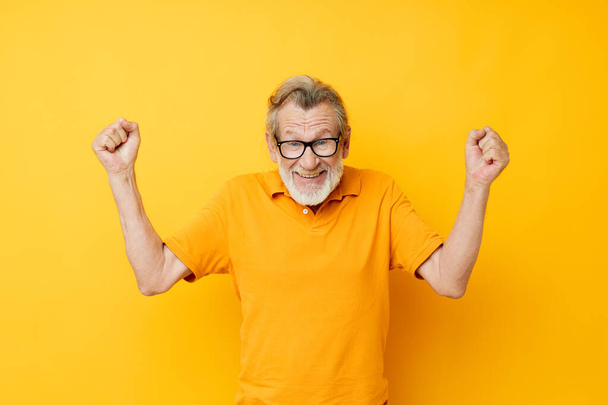 Portrait of happy senior man posing yellow tshirt glasses cropped view - Photo, Image