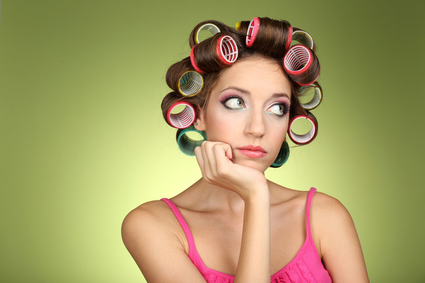 Beautiful girl in hair curlers on green background - Foto, Imagem