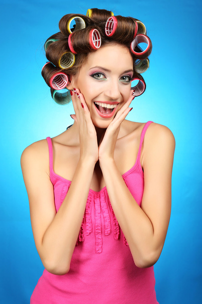 Beautiful girl in hair curlers on blue background - Фото, изображение