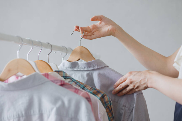 a womans hand takes a hanger with clothes clothes for a business meeting or dinner. a female stylist picks up pride - Foto, imagen