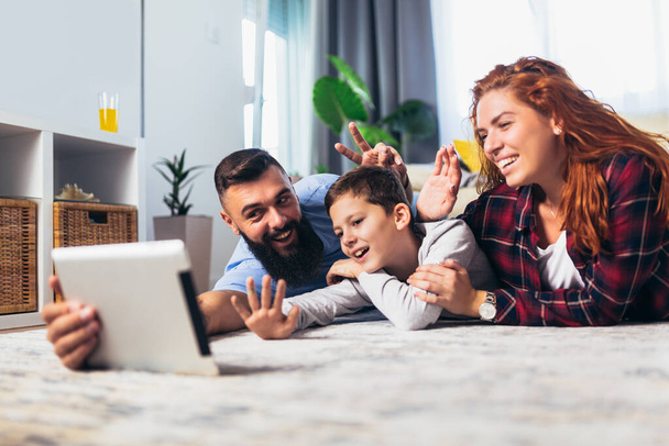 カーペットの上に横たわるとデジタル タブレットを使用して 1 つの子と幸せな家庭 - 写真・画像