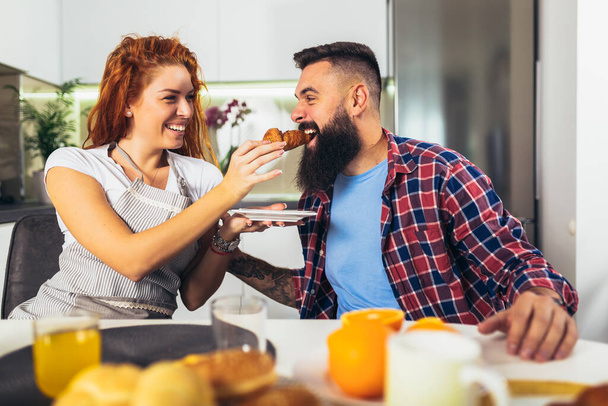 Happy couple having breakfast together in the kitchen - Photo, Image