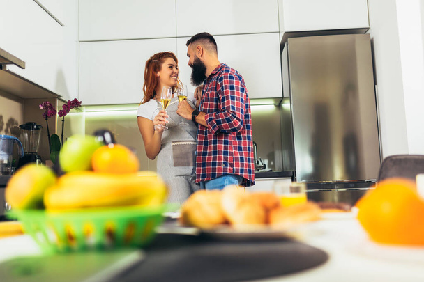 Jeune couple amoureux boire du vin dans la cuisine de la maison - Photo, image