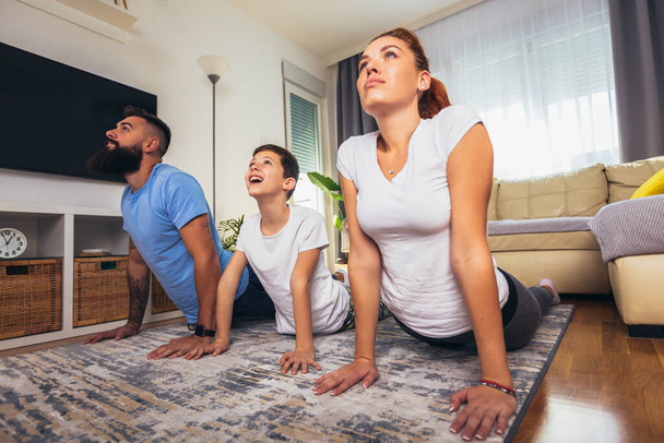 Healthy morning stretching - Mother and father with son doing gymnastic exercise at home - 写真・画像