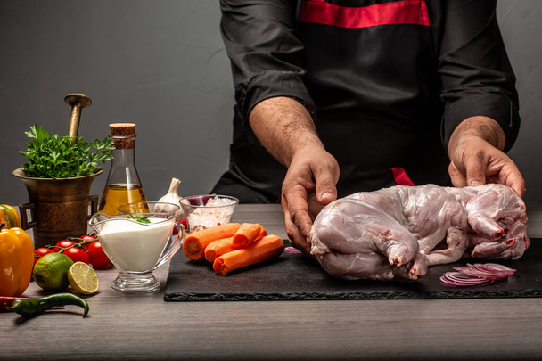 Шеф-кухар наливає вершковий соус на кроляче м'ясо, процес приготування їжі, руки шеф-кухаря, який готує дикого кролика, рецепт приготування м'яса кролика, фон харчового рецепту. простір для тексту
. - Фото, зображення