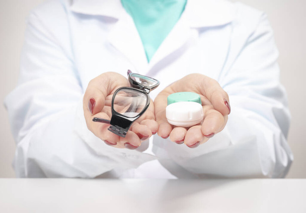 Doctor Ophthalmologist holding glasses and contact lenses. choosing between contact lenses or glasses. Eyesight correction. Ophthalmology, excellent vision or optician shop concept - Photo, Image