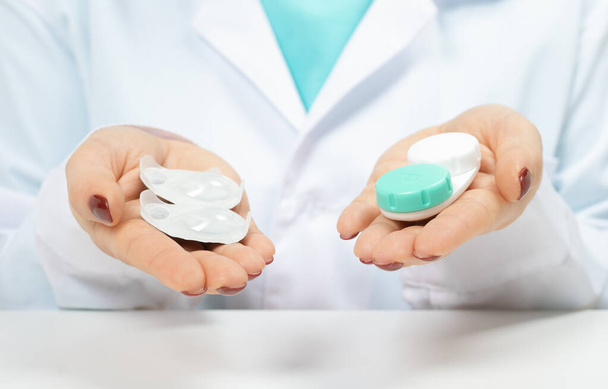 Doctor Ophthalmologist holding in hands one-day contact lenses and reusable contact lenses. choosing between types of contact lenses . myopia and eyesight problem concept. close-up - Fotó, kép