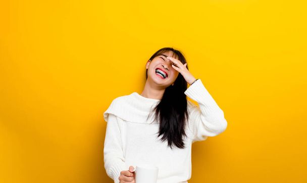 Asian woman laughing hard and having a lot of happiness holding a white coffee cup The concept of laughing and having a bright smile. - 写真・画像