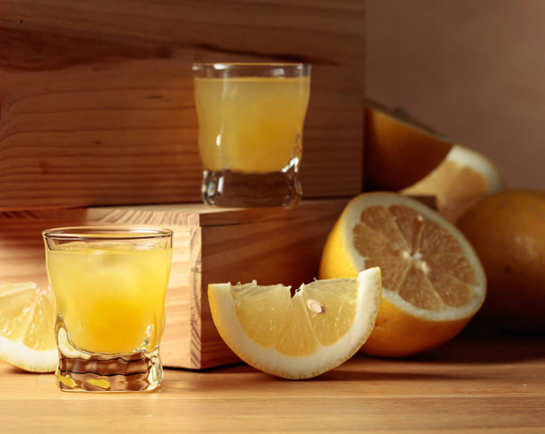 Traditional homemade lemon liqueur limoncello and fresh citrus on a wooden table. - Zdjęcie, obraz