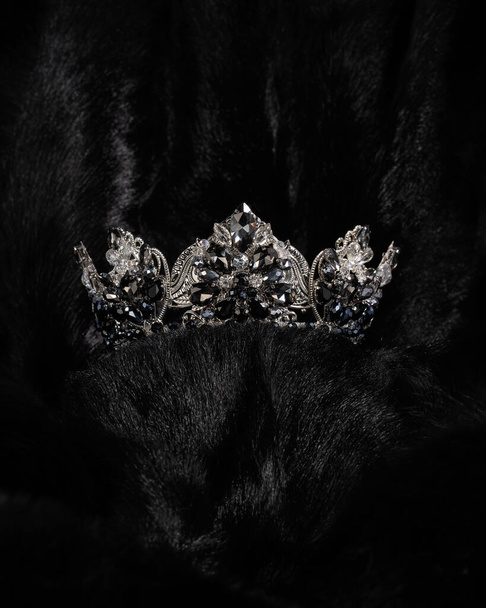 schöne silberne Krone mit schwarzem Stein für Miss Schönheitswettbewerb auf schwarzem, glänzendem Hintergrund, Nahaufnahme - Foto, Bild