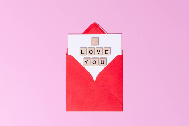 Top view of red envelope with wooden letters words I love you on a pink background. St Valentine Day letter concept.  - Fotoğraf, Görsel