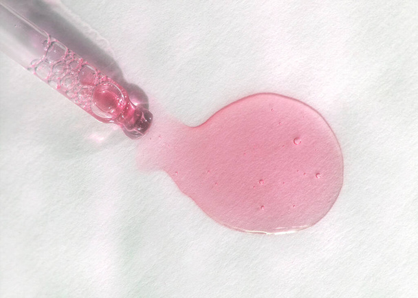 Піпетка з рожевою рідиною гіалуроновою кислотою на білому тлі. Концепція косметики та охорони здоров'я крупним планом
 - Фото, зображення