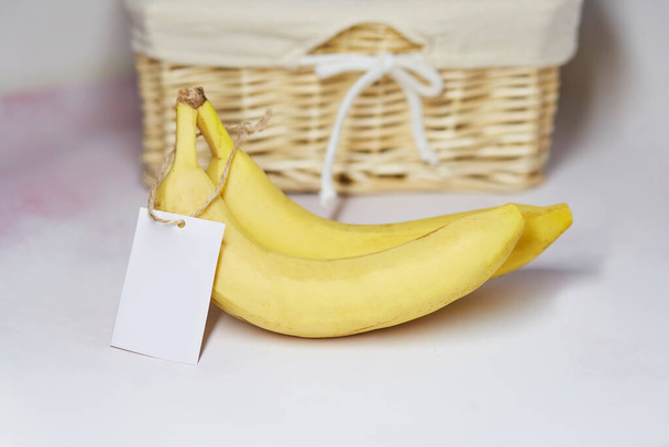 Etichetta finta sulle banane. Prodotto adesivo per testo o prezzo. Cesto di vimini sullo sfondo. Prodotti agricoli biologici provenienti dal mercato locale. Copia spazio - Foto, immagini