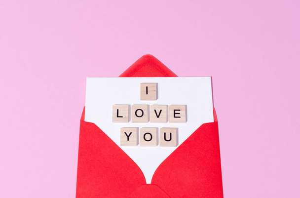Red envelope with wooden words I love you on a pink pastel copy space background. St Valentines Day letter concept.  - Fotografie, Obrázek