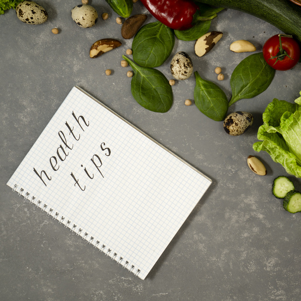 Plan de dieta con verduras y verduras frescas en un cuaderno de papel sobre una superficie de mesa gris. - Foto, imagen