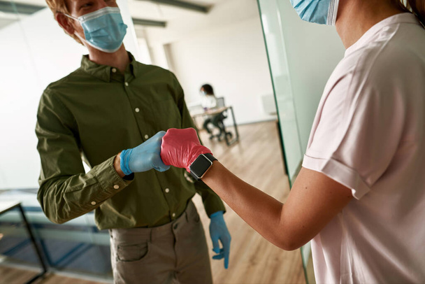 Guy and woman bumping fists in medical gloves - 写真・画像