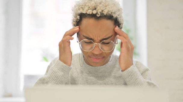 Primer plano de la mujer africana que tiene dolor de cabeza mientras usa el ordenador portátil - Foto, Imagen