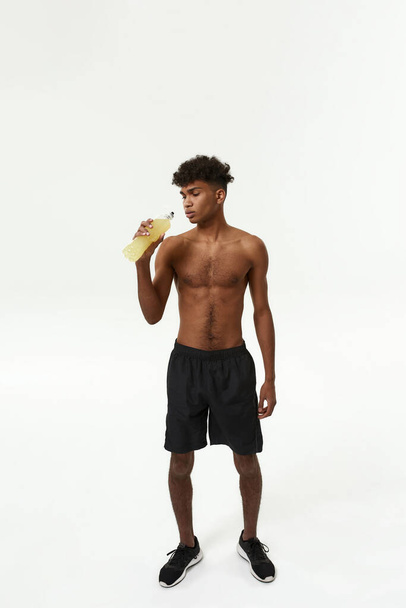 Black sportsman drinking sport drink from bottle - Foto, Imagen