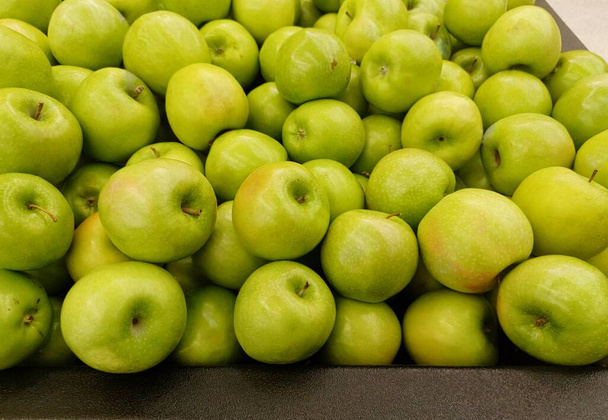 Olgun büyükanne Smith elmaları gevşek bir şekilde geleneksel sebze pazarı görünümüne dağılmış, yakın plan görüntüsü.. - Fotoğraf, Görsel
