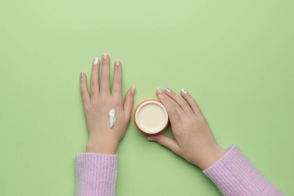 A girl in a warm sweater puts cream on her hands. The concept of using cosmetics. Flat lay. - Valokuva, kuva