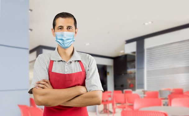 Happy bartender with red apron working in a bar wearing a face mask to prevent the spread of coronavirus - COVID-19 lifestyle concepts and copy space. - Foto, imagen