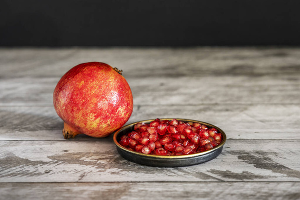 Red pomegranate with ripe grains on vintage metal plate - Foto, immagini