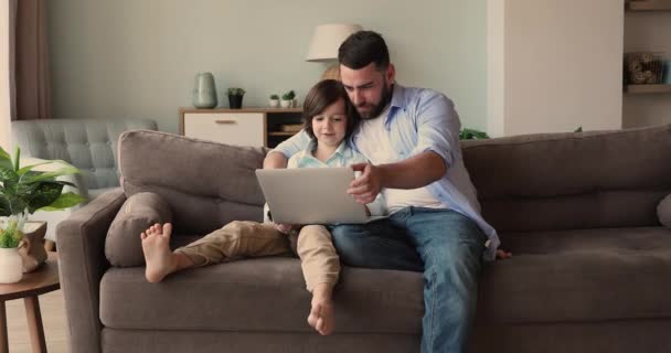 Padre premuroso giocare al videogioco sul computer portatile con figlio felice - Filmati, video