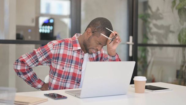 African Man έχοντας πόνο στην πλάτη κατά τη χρήση Laptop - Φωτογραφία, εικόνα