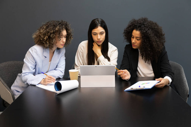 Succesvolle zakenvrouwen die tijdens een vergadering in een bureau zitten en een digitale tablet gebruiken. - Foto, afbeelding