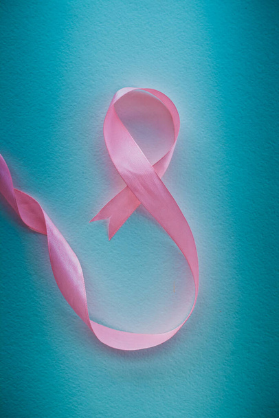 pink ribbon in the shape of an eight on a blue background. the concept of congratulations on Mothers Day. a postcard for international Womens Day, the concept of a holiday on international womens - Фото, зображення