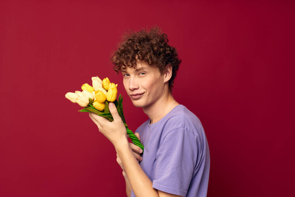 teenager holding a yellow bouquet of flowers purple t-shirts isolated background unaltered - Photo, image