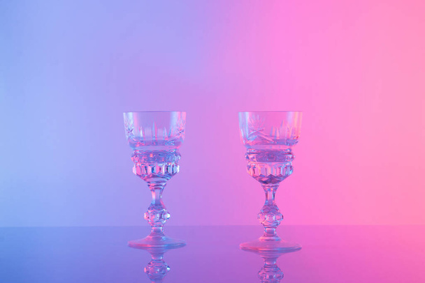 Two glasses for drink a color neon background. Minimal concept. - Φωτογραφία, εικόνα