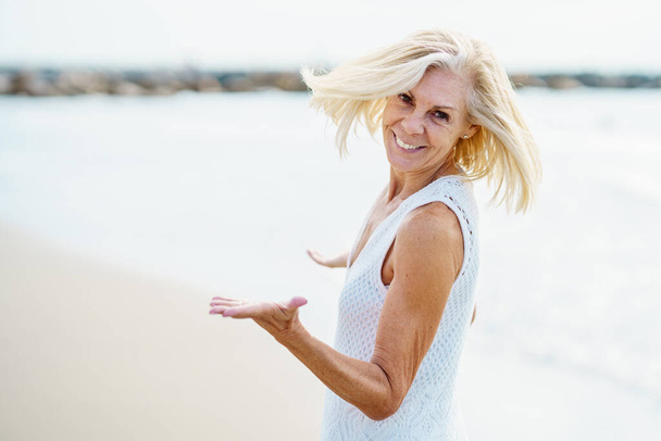 Szczęśliwa dojrzała kobieta spacerująca po plaży, spędzająca wolny czas, ciesząca się wolnym czasem - Zdjęcie, obraz