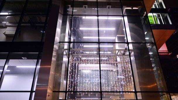 Edificio de oficinas por la noche; fachada del edificio con cristal y luces. Fondo con rascacielos modernos iluminados. - Foto, Imagen