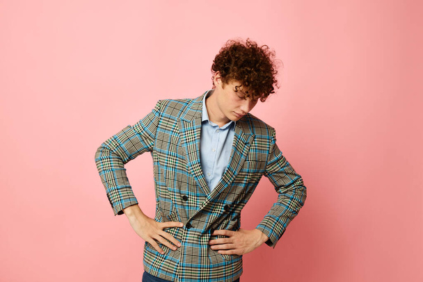 portrait of a young curly man checkered blazer elegant style posing fashion pink background unaltered - Zdjęcie, obraz