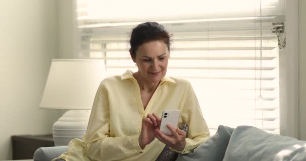 Older woman use smartphone swipe news feed, choose online goods - Кадры, видео