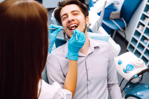 Young man at the dentist's chair during a dental procedure. Overview of dental caries prevention. Healthy teeth and medicine concept. - Foto, Imagem