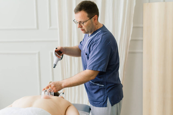 Žena provádí masáž kyčle s vakuovou nádobkou pro masáž proti celulitidě. - Fotografie, Obrázek